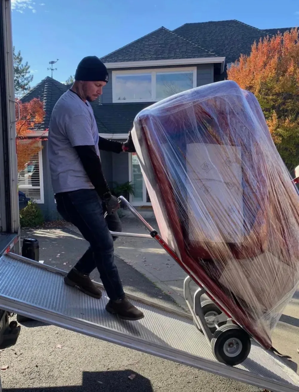 Mover carrying wrapped furniture up a truck ramp